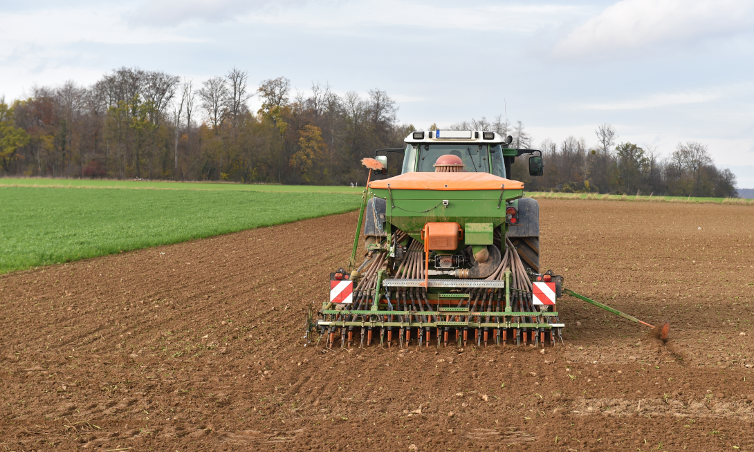 Ein Traktor fährt auf einem Feld mit einer angehängten Sämaschine.