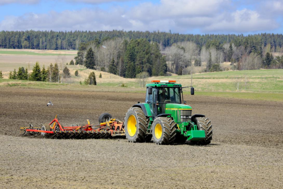 Arbeiten auf dem Feld mit dem Traktor John Deere 7710 und dem Saatbettgrubber Potila Magnum 800 Plus an einem Frühlingstag. 